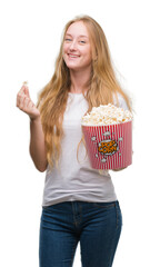 Canvas Print - Blonde teenager woman eating pop corn with a happy face standing and smiling with a confident smile showing teeth