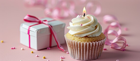 Poster - A cupcake topped with a lit candle beside a white gift box against a pink backdrop creating a charming copy space image