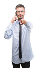 Canvas Print - Young business adult man talking on the phone pointing with finger to the camera and to you, hand sign, positive and confident gesture from the front