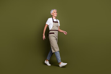 Sticker - Full length photo of charming excited woman wear apron serving coffee walking empty space isolated khaki color background