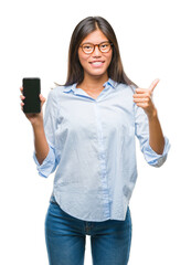 Poster - Young asian woman showing smartphone blank screen over isolated background happy with big smile doing ok sign, thumb up with fingers, excellent sign