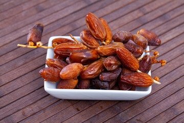 Wall Mural - Closeup of dried dates in plate on wooden background. Concept of healthy eating