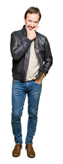 Wall Mural - Middle age handsome man wearing black leather jacket looking confident at the camera with smile with crossed arms and hand raised on chin. Thinking positive.