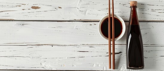 Poster - Chopsticks resting on a white wooden table beside a bottle of soy sauce creating a serene setting for a copy space image