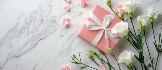 Wall Mural - Top view of white eustoma flowers and a pink gift box on a background for a holidays greeting card concept with copy space image