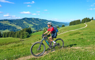 Wall Mural - nice active senior woman riding her electric mountain bike at Mount Huendle in Oberstaufen, Allgaeu Alps , Bavaria, Germany