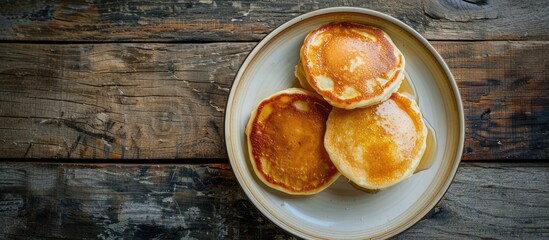 Wall Mural - Top view of freshly baked pancakes plated on a white dish set on a rustic wooden surface with a grunge retro style showcasing a close up shot with copy space image