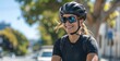 © TigerDude - Smiling woman in cycling gear, wearing sunglasses and helmet while riding on the street with a city background