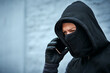 © peopleimages.com - Mask, thief or man with phone call for talking, provide instructions and demand ransom for complete mission. Outdoor, male criminal and mobile with face cover for identity protection, hide and fraud