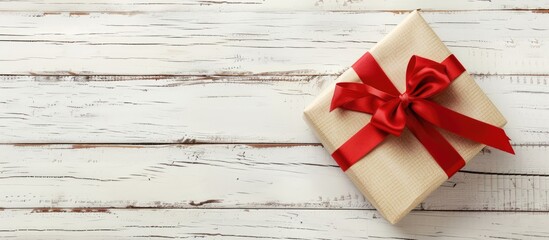 Sticker - Christmas gift in a holiday box with a red ribbon on a white wooden background providing copy space image