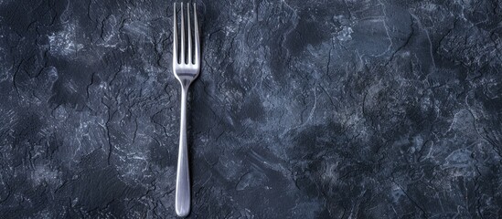 Poster - New stainless steel kitchen fork on black table background with copy space image