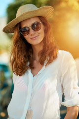 Poster - Woman, hat and sunglasses in outdoor with smile for vacation, travel or relax in Thailand. Female tourist, nature or happiness for holiday in tropical climate with lens flare, journey with sun safety