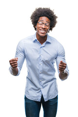 Canvas Print - Afro american business man wearing glasses over isolated background very happy and excited doing winner gesture with arms raised, smiling and screaming for success. Celebration concept.