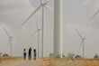 © Montri - Workers talking by wind turbines in rural landscape. Technician discussing with engineers about wind turbine. Renewable energy from the wind.