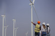 © Montri - Workers talking by wind turbines in rural landscape. Technician discussing with engineers about wind turbine. Renewable energy from the wind.