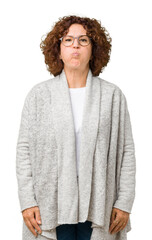 Wall Mural - Beautiful middle ager senior woman wearing jacket and glasses over isolated background puffing cheeks with funny face. Mouth inflated with air, crazy expression.