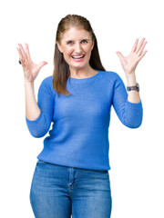 Wall Mural - Beautiful middle age mature woman wearing winter sweater over isolated background celebrating mad and crazy for success with arms raised and closed eyes screaming excited. Winner concept