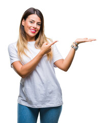 Canvas Print - Young beautiful woman casual white t-shirt over isolated background amazed and smiling to the camera while presenting with hand and pointing with finger.