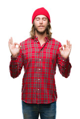 Canvas Print - Young handsome man with long hair wearing red cap over isolated background relax and smiling with eyes closed doing meditation gesture with fingers. Yoga concept.