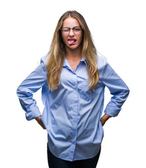 Wall Mural - Young beautiful blonde business woman wearing glasses over isolated background sticking tongue out happy with funny expression. Emotion concept.