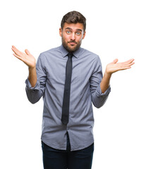 Canvas Print - Young handsome business man over isolated background clueless and confused expression with arms and hands raised. Doubt concept.