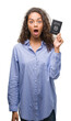 © Krakenimages.com - Young hispanic woman holding passport of Italy scared in shock with a surprise face, afraid and excited with fear expression