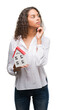 © Krakenimages.com - Young hispanic real state agent woman holding small house serious face thinking about question, very confused idea