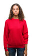 © Krakenimages.com - Young hispanic woman wearing red sweater with serious expression on face. Simple and natural looking at the camera.