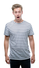 Sticker - Young handsome blond man wearing stripes sailor t-shirt scared in shock with a surprise face, afraid and excited with fear expression