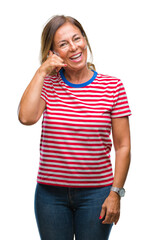 Wall Mural - Middle age senior hispanic woman over isolated background smiling doing phone gesture with hand and fingers like talking on the telephone. Communicating concepts.