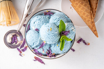 Wall Mural - Colorful sweet butterfly pea  blue matcha scoops in portioned bowl, frozen healthy trendy sorbet dessert with waffle ice cream cones and dried butterfly pea flowers