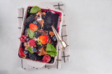 Wall Mural - Homemade sweet berry cobbler pie cake with various garden forest berries - strawberry, blackberry, blueberry, healthy summer dessert recipe in baking pan and plate, copy space