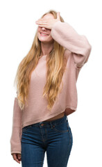 Canvas Print - Blonde teenager woman wearing pink sweater smiling and laughing with hand on face covering eyes for surprise. Blind concept.