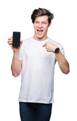 Sticker - Young man showing smartphone screen over isolated background with surprise face pointing finger to himself