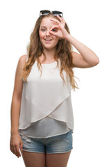 Poster - Young blonde woman wearing sunglasses doing ok gesture with hand smiling, eye looking through fingers with happy face.