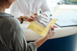 © CanBorg/peopleimages.com - Car dealership, woman and hands with flyer for motor purchase and brochure for shopping. Showroom, deal and retail sale document at customer consultation meeting with reading an advertisement