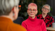 © KC Radler - Woman with pink hair and red glasses listening intently to someone during a group therapy session