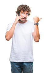 Poster - Handsome hispanic man model talking on smartphone over isolated background pointing and showing with thumb up to the side with happy face smiling