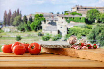 Wall Mural - Blurred beautiful Tuscany countryside houses and green fields and gardens background. Wooden table background with copy space for products and food and for montage objects display.