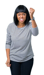 Poster - Beautiful young african american woman wearing stripes sweater over isolated background angry and mad raising fist frustrated and furious while shouting with anger. Rage and aggressive concept.