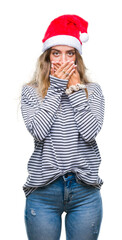 Poster - Beautiful young blonde woman wearing christmas hat over isolated background shocked covering mouth with hands for mistake. Secret concept.