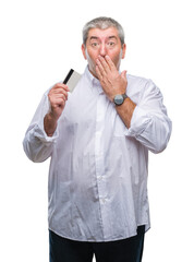 Sticker - Handsome senior man holding credit card over isolated background cover mouth with hand shocked with shame for mistake, expression of fear, scared in silence, secret concept