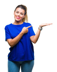 Poster - Young beautiful woman wearing casual blue t-shirt over isolated background amazed and smiling to the camera while presenting with hand and pointing with finger.