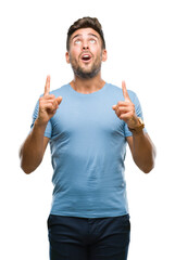 Poster - Young handsome man over isolated background amazed and surprised looking up and pointing with fingers and raised arms.