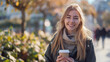 © Neyro - Young woman holding a cup of coffee outdoors, smiling and enjoying fresh air, beautiful urban landscape with copy space