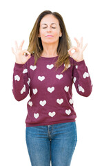 Sticker - Beautiful middle age woman wearing hearts sweater over isolated background relax and smiling with eyes closed doing meditation gesture with fingers. Yoga concept.