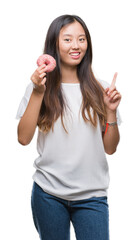 Poster - Young asian woman eating donut over isolated background surprised with an idea or question pointing finger with happy face, number one