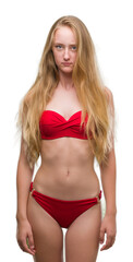 Poster - Blonde teenager woman wearing red bikini skeptic and nervous, frowning upset because of problem. Negative person.