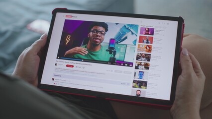 Poster - Caucasian woman watches educational video of blogger about 3D modeling using tablet computer while lying on sofa. Tablet screen shows video hosting website interface with video content. Close Up.