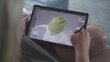 © Framestock - Woman draws and creates clothes in 3D modeling design application using digital tablet and stylus. Caucasian woman makes remote work project lying on couch at home. Lifestyle and freelance. Close Up.